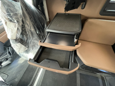 Mack truck interior showing center console storage with open drawers and brown seats.