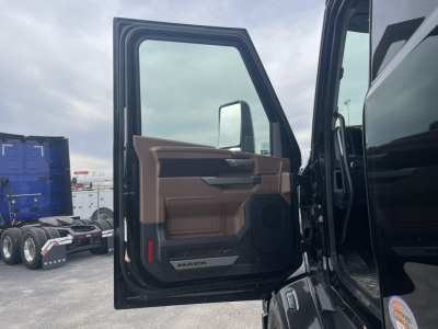Truck cab door interior panel with Mack logo and window, view into open door of 2026 Mack PR64T76H sleeper truck