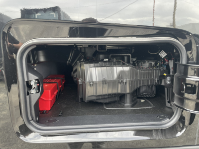 Mack PR64T76H sleeper truck engine bay showing air intake, battery pack, and compressor housing in storage compartment