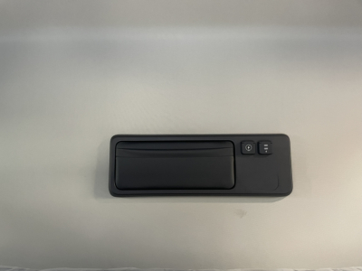 Interior sun visor with vanity mirror and two control buttons in a Mack PR64T76H truck cabin, hand-sized panel mounted on light grey surface.