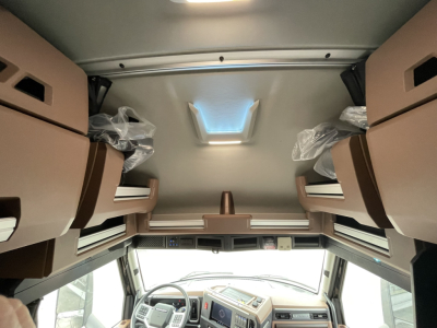 Interior view of a new Mack PR64T76H truck sleeper cab showing beige bunk seats and center console. VIN 1M1PR4GY8TM100898 and stock 71451 visible.