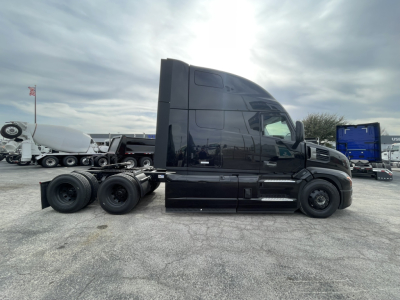 Back side view of a black Mack PR64T76H conventional sleeper tractor in a parking lot.