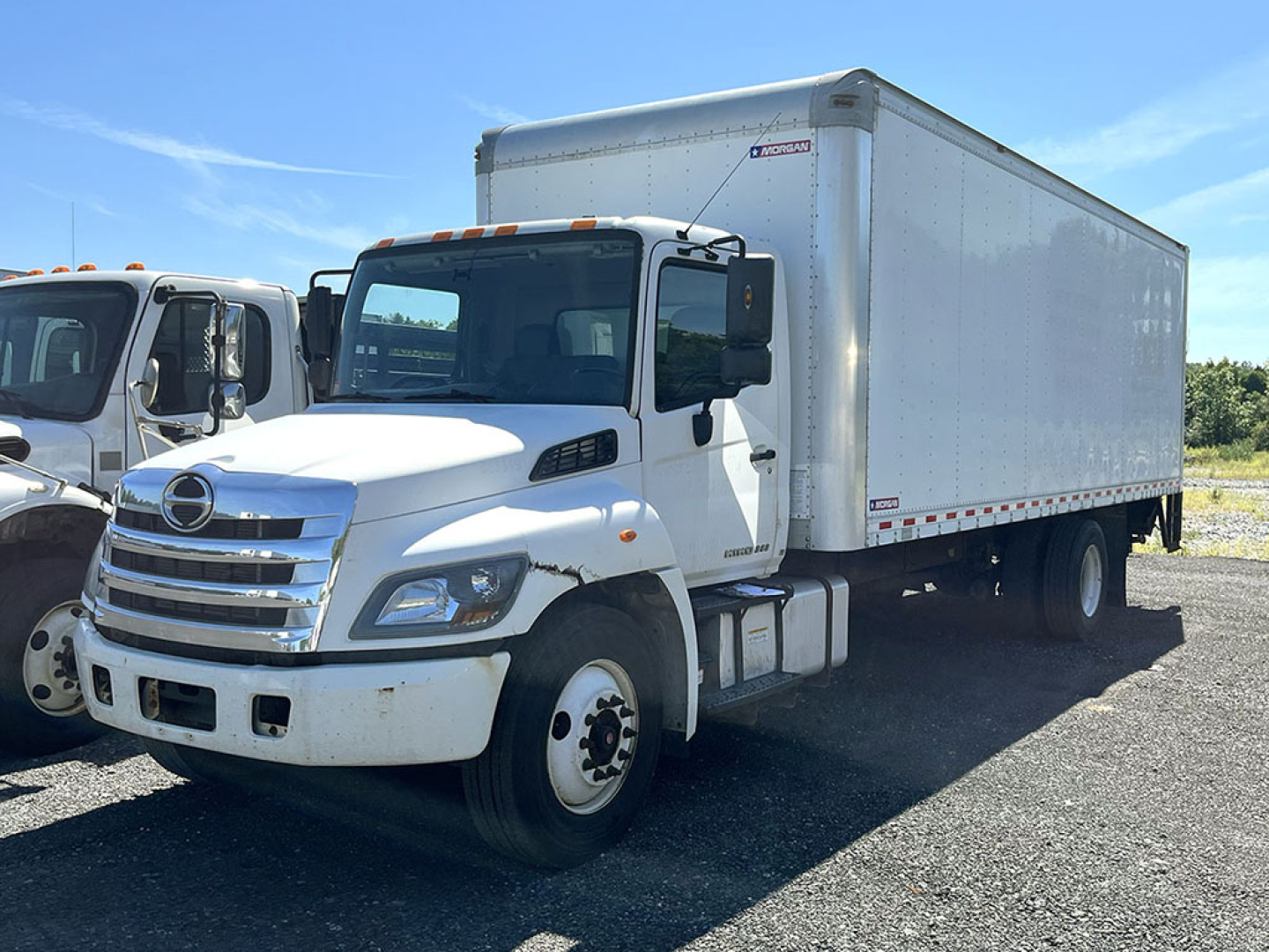 2018 Hino 268 box truck with white cab and aluminum cargo box, side view shows Hino emblem on grille, daylight conditions, no visible text on doors or sides besides generic truck features.