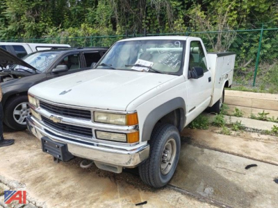 Chevrolet C/K 3500 series utility truck in white, front-left view, utility bed on back, parked on concrete.
