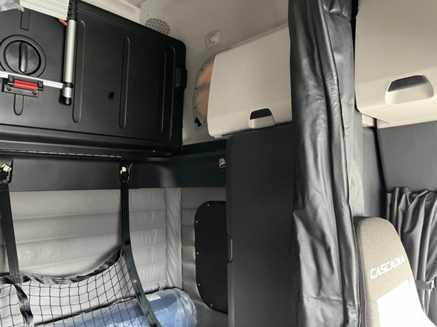 Freightliner Cascadia 126 truck interior sleeper area with storage cabinet, bunk area, and cab upholstery visible