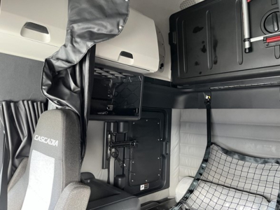 Seat area of a Freightliner Cascadia 126 cabin showing sleeper compartment and storage panels with embedded text 'Cascadia' on seat.