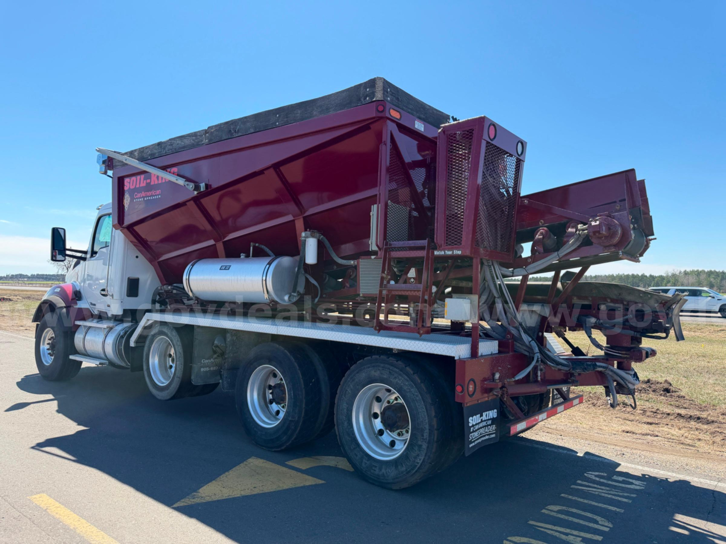 Kenworth T880 dump truck in-service with red dump body and multiple axles, side view.
