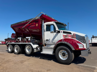Kenworth T880 dump truck in service with maroon dump body, American flag graphics on cab, three rear axles, side view showing front chrome bumper and steps.