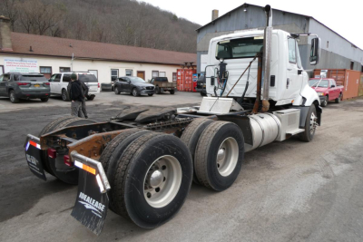 Truck chassis showing rear wheels and International ProStar cab in background; fuel tanks and rear mud flaps visible.