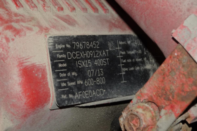 Plate with engine and vehicle information tags on a red International ProStar cab area showing model 1SX15 400ST and serial numbers.