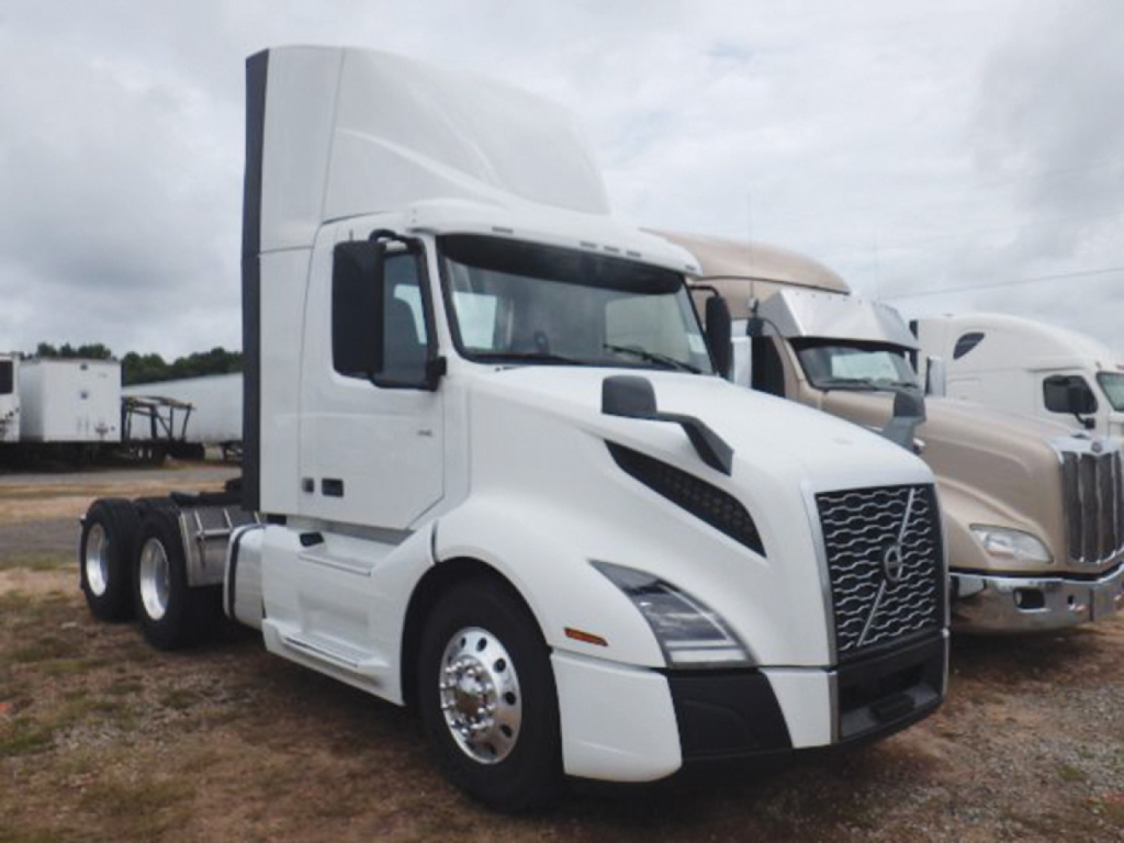 Truck cab showing Volvo VNL-style front end with white paint, aerodynamic mirrors, and large grille. No visible text on the image.