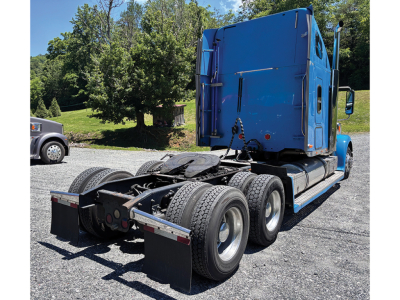 Blue Freightliner Coronado tractor cab with rear view showing fifth wheel, dual rear axles, and mud flaps; no visible text on components.