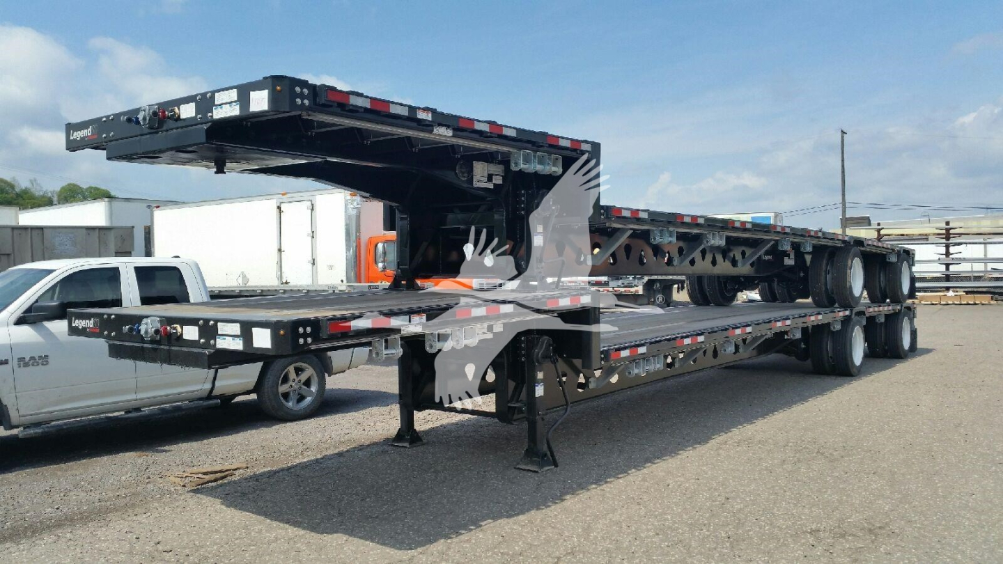 Manac drop deck trailer showing multi-axle flatbed with support legs and loading ramps.