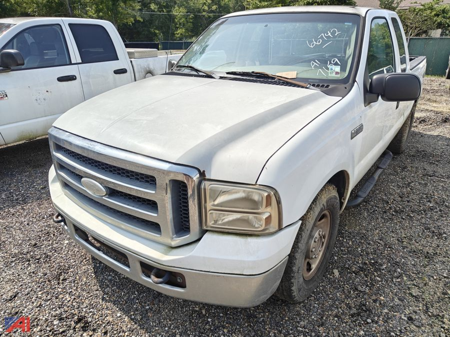 2005 Ford F-250 Super Duty extended cab pickup truck, white, front grille, headlights, and side mirrors, parked on gravel lot