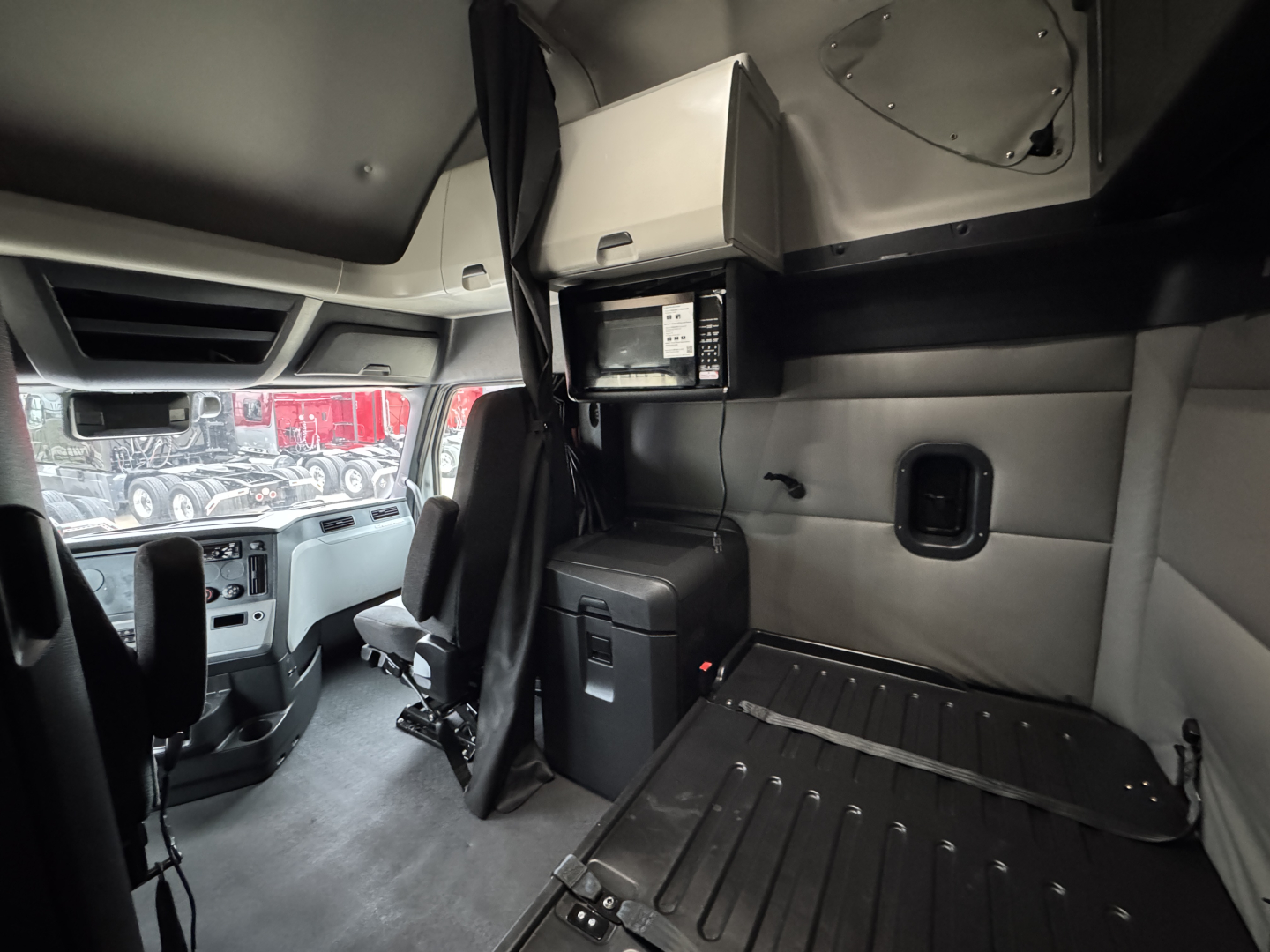 Interior of Freightliner PT126064ST sleeper cab showing driver seat area, overhead console, storage cabinet, and cargo platform.