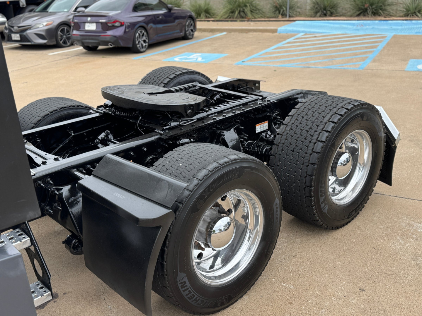 Rear chassis of a Freightliner truck showing dual rear axles and large tires with chrome wheels and fenders.