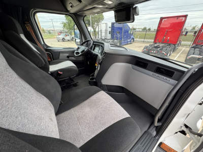 Cab interior of a Freightliner PT126064ST showing front seats, dashboard, steering wheel, and Passenger side door panel with Slim glove compartment.
