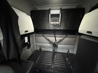 Conventional sleeper cab interior of a Freightliner PT126064ST showing rear cargo area with tie-down straps and side panels.