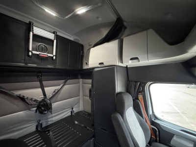 Cab interior of Freightliner sleeper tractor showing bunk area and storage compartments.
