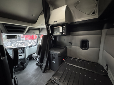 Interior of Freightliner PT126064ST sleeper cab showing driver seat area, overhead console, storage cabinet, and cargo platform.