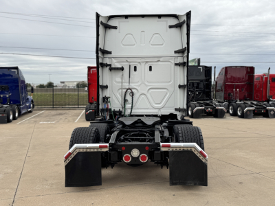 Rear view of Freightliner tractor chassis showing fifth wheel with dual rear axles and mud flaps.
