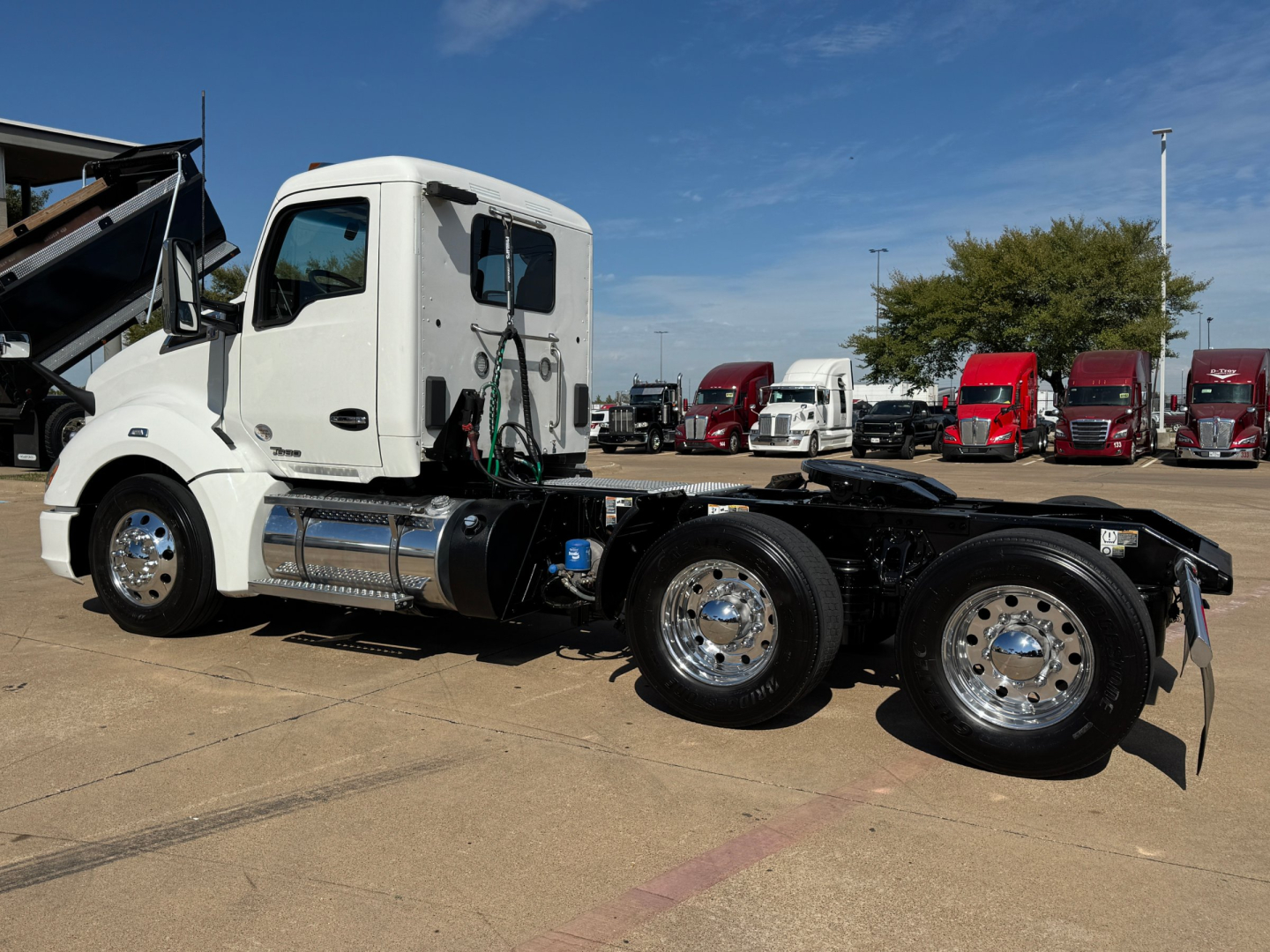 Kenworth T680 conventional daycab tractor shown in profile with white cab and dual rear axles, parked at dealership lot.
