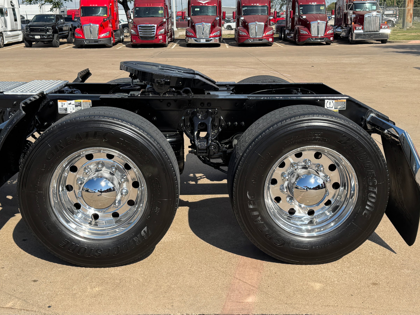 Kenworth T680 semi truck chassis side view showing dual rear axles with chrome wheels and tires, cab not visible