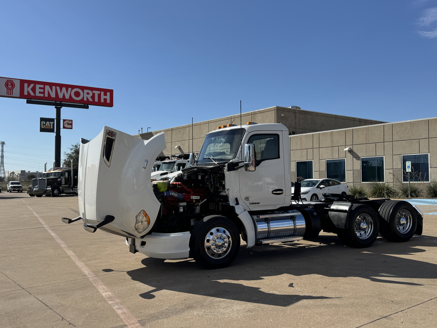 Kenworth T680 front with hood open showing engine bay and chrome fuel tanks.