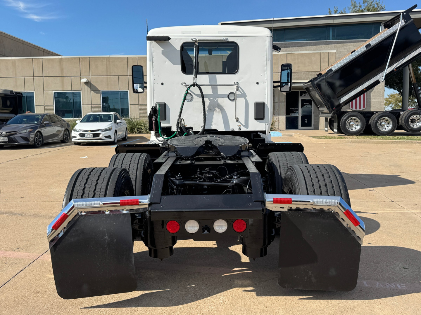 Kenworth T680 rear view showing chassis and mudflaps with hitch and hydraulic lines.