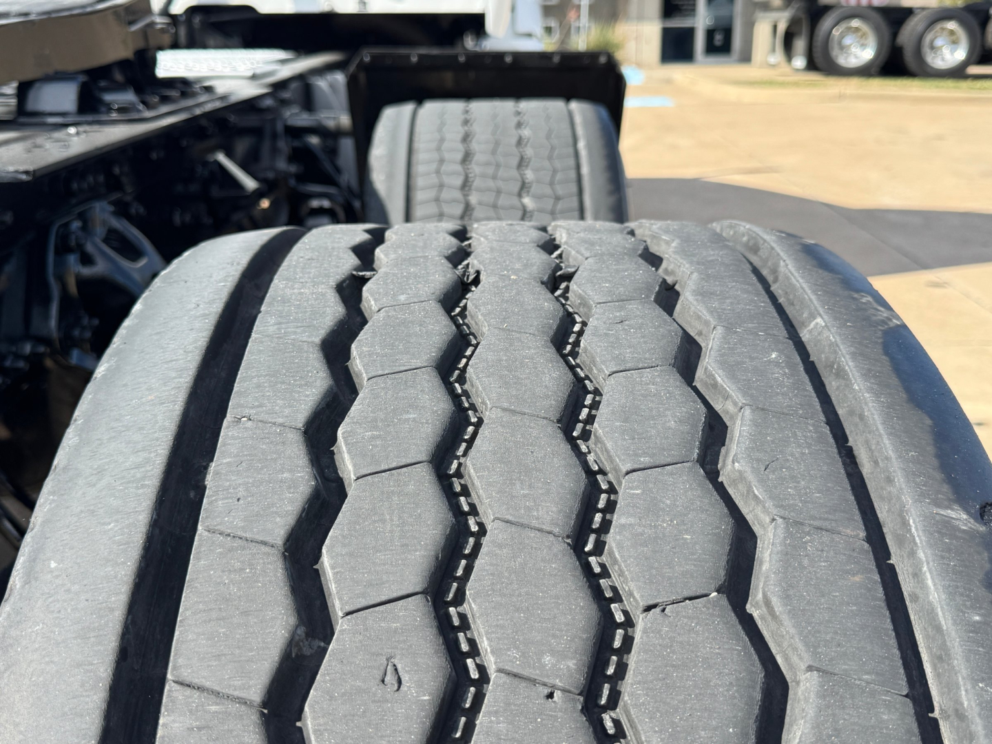 Kenworth T680 wheel/tire close-up showing tread with no visible damage; front dual rear axle area and CV joint in background.
