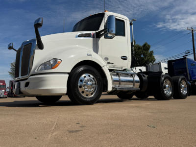 Kenworth T680 conventional daycab showing front left angle with chrome fuel tanks and cab mirrors.