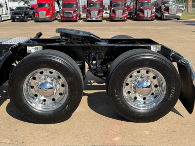 Kenworth T680 semi truck chassis side view showing dual rear axles with chrome wheels and tires, cab not visible