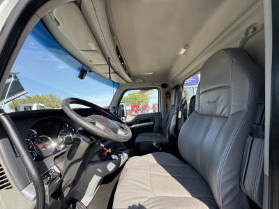 Interior of 2022 Kenworth T680 cab showing steering wheel, dashboard, and driver seat with light gray upholstery.