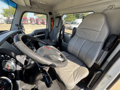 Kenworth T680 interior showing steering wheel, driver seat, and dashboard in view with gray upholstery.