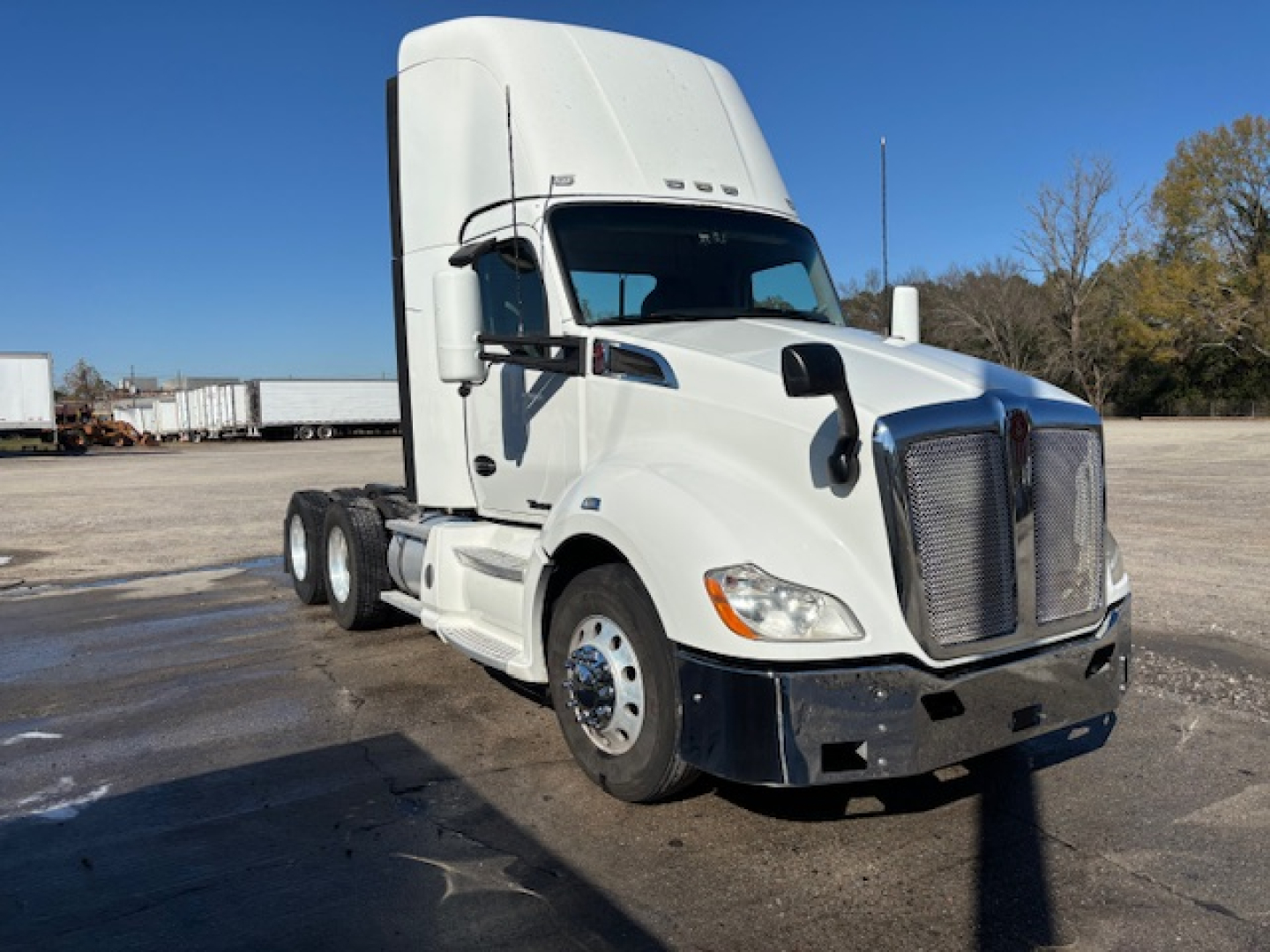 Truck engine bay view of a white 2020 Kenworth T680 day cab showing front grille, headlights, and bumper.