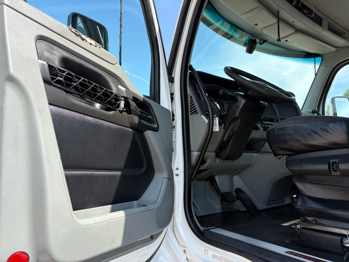 Kenworth T880 truck cab interior and open door showing dashboard, steering wheel, and seat with black trim.