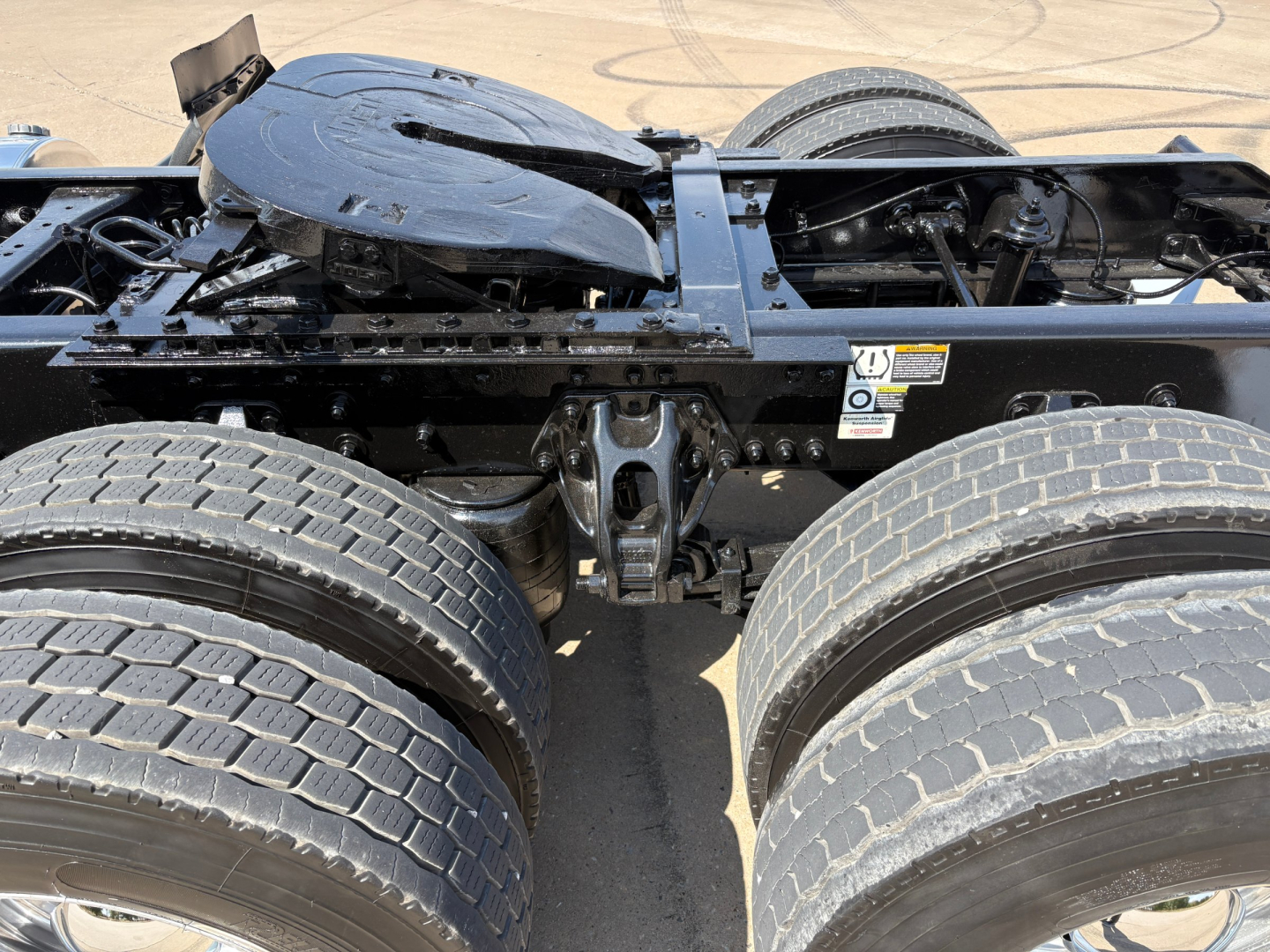 Kenworth T880 chassis showing air tanks and dual rear axles; exposed frame and fifth wheel area with hoses and wiring visible.