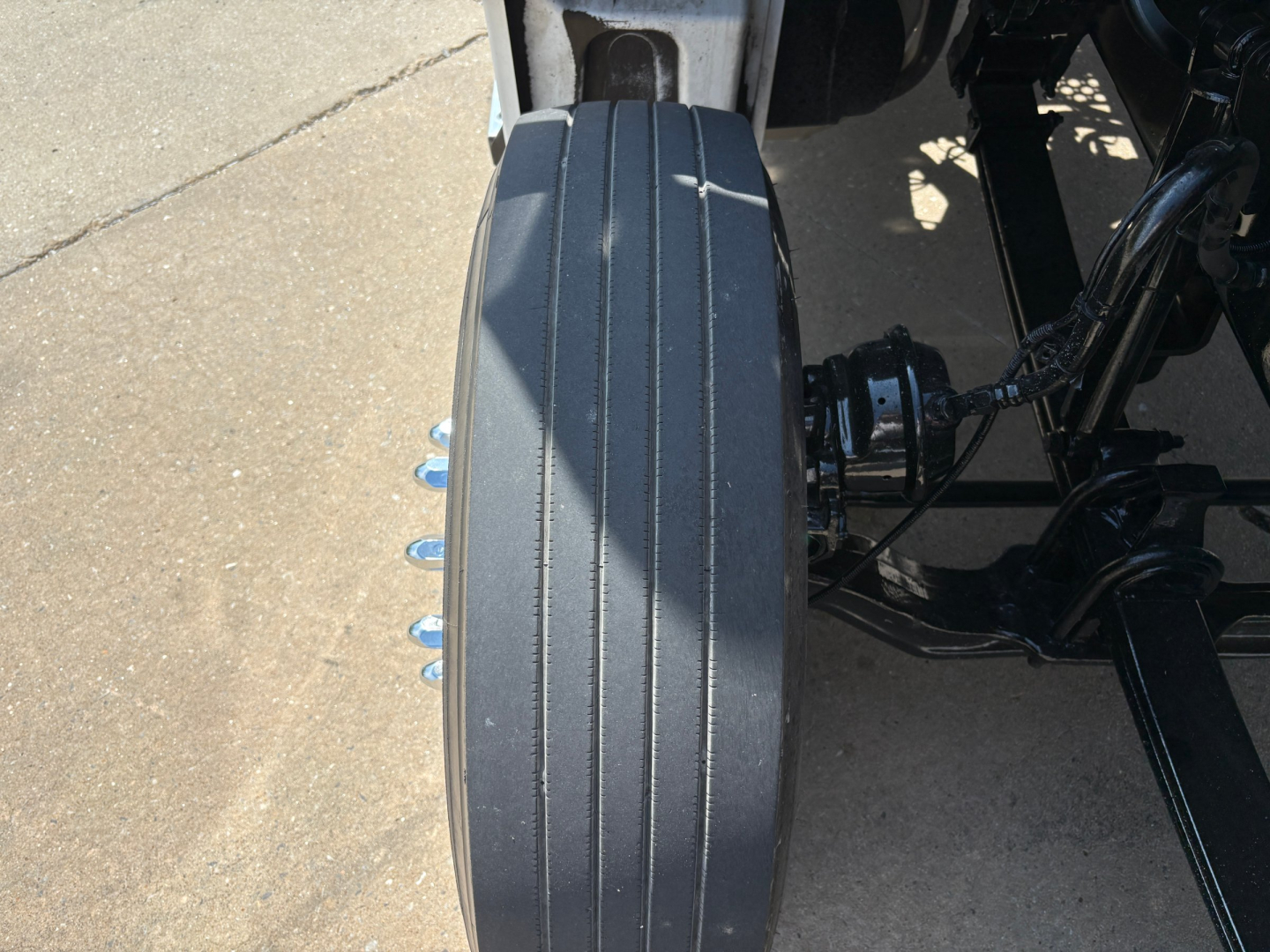 Kenworth T880 chassis rear view showing fuel rail/air lines and wheel hub area with vertical groove fender and suspension components.