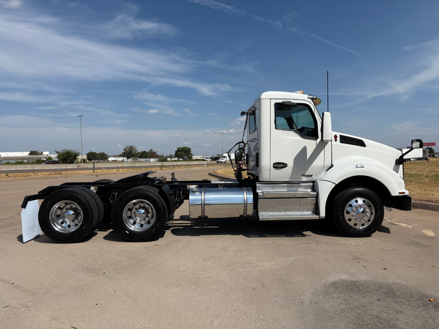 Kenworth T880 daycab tractor in white, side view showing fuel tanks, dual rear axles, and chrome wheels.