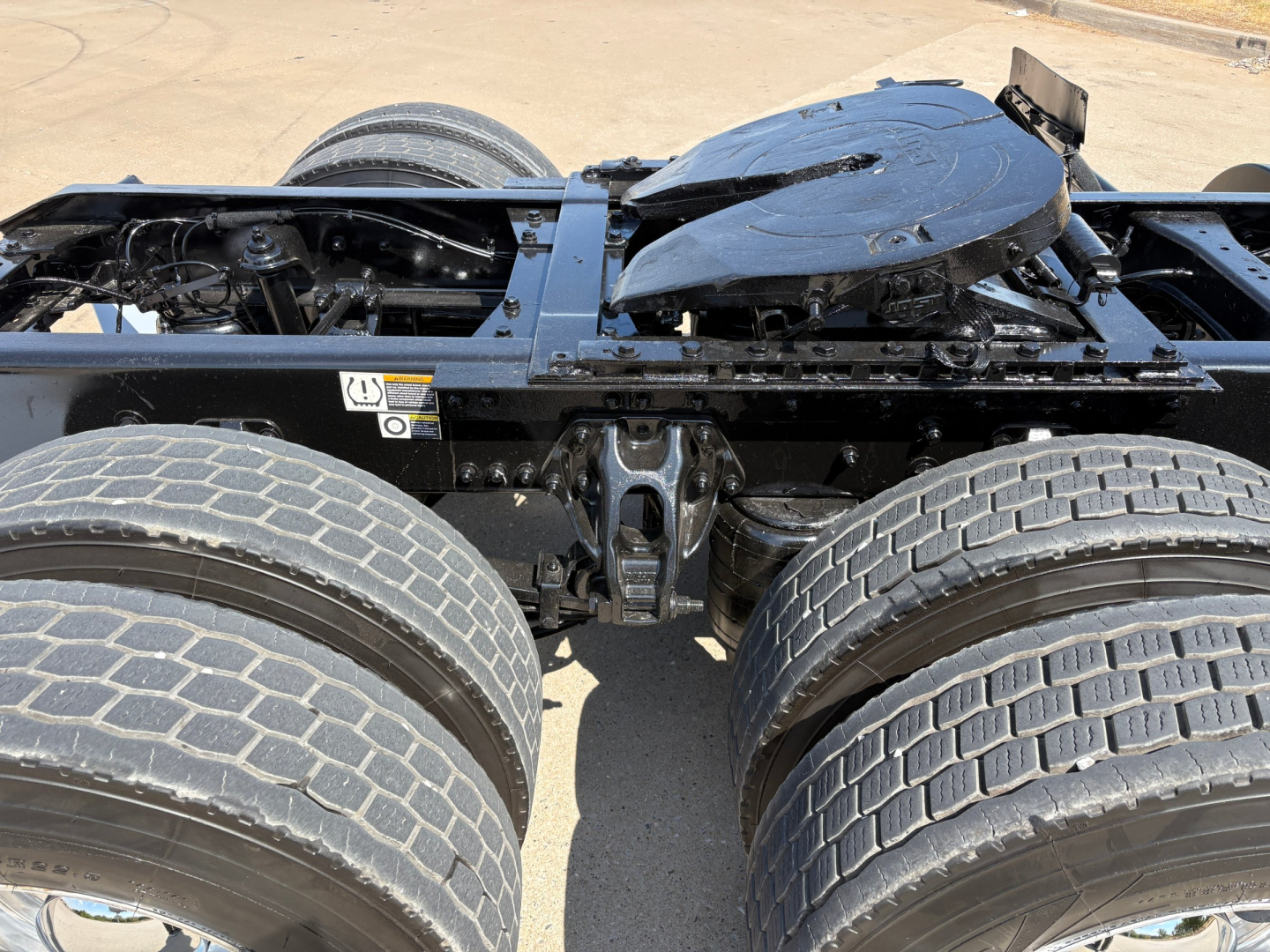 Kenworth T880 chassis view showing dual rear axles and fifth wheel mounting with exposed frame and suspension components.