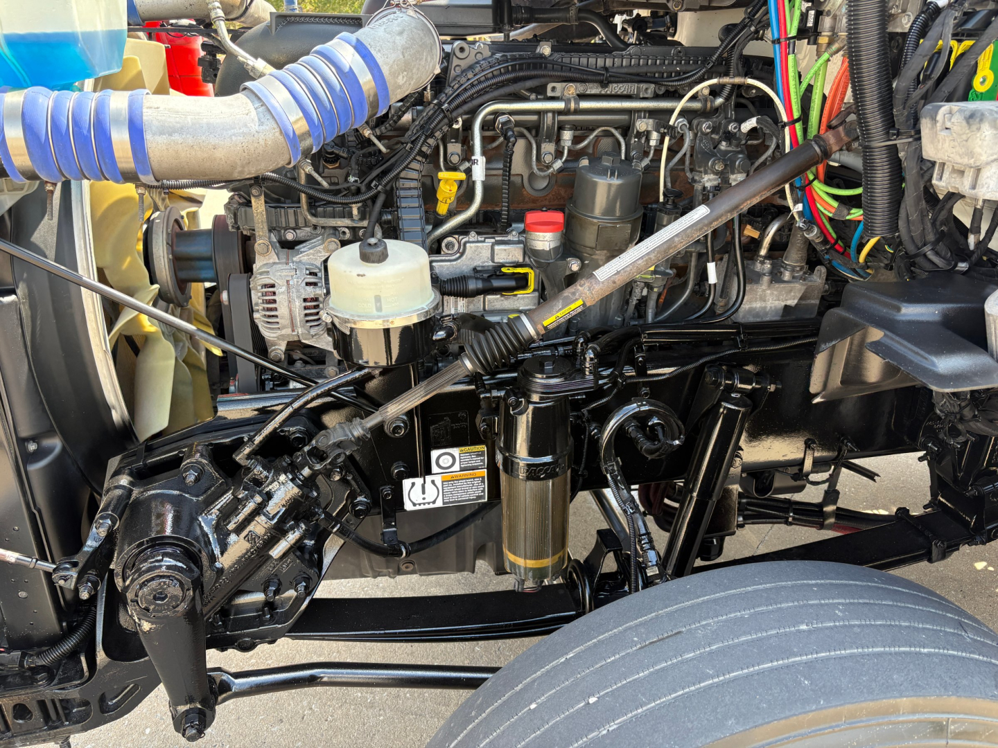 Kenworth T880 engine bay showing visible fuel filter, hoses, wiring, and radiator area.