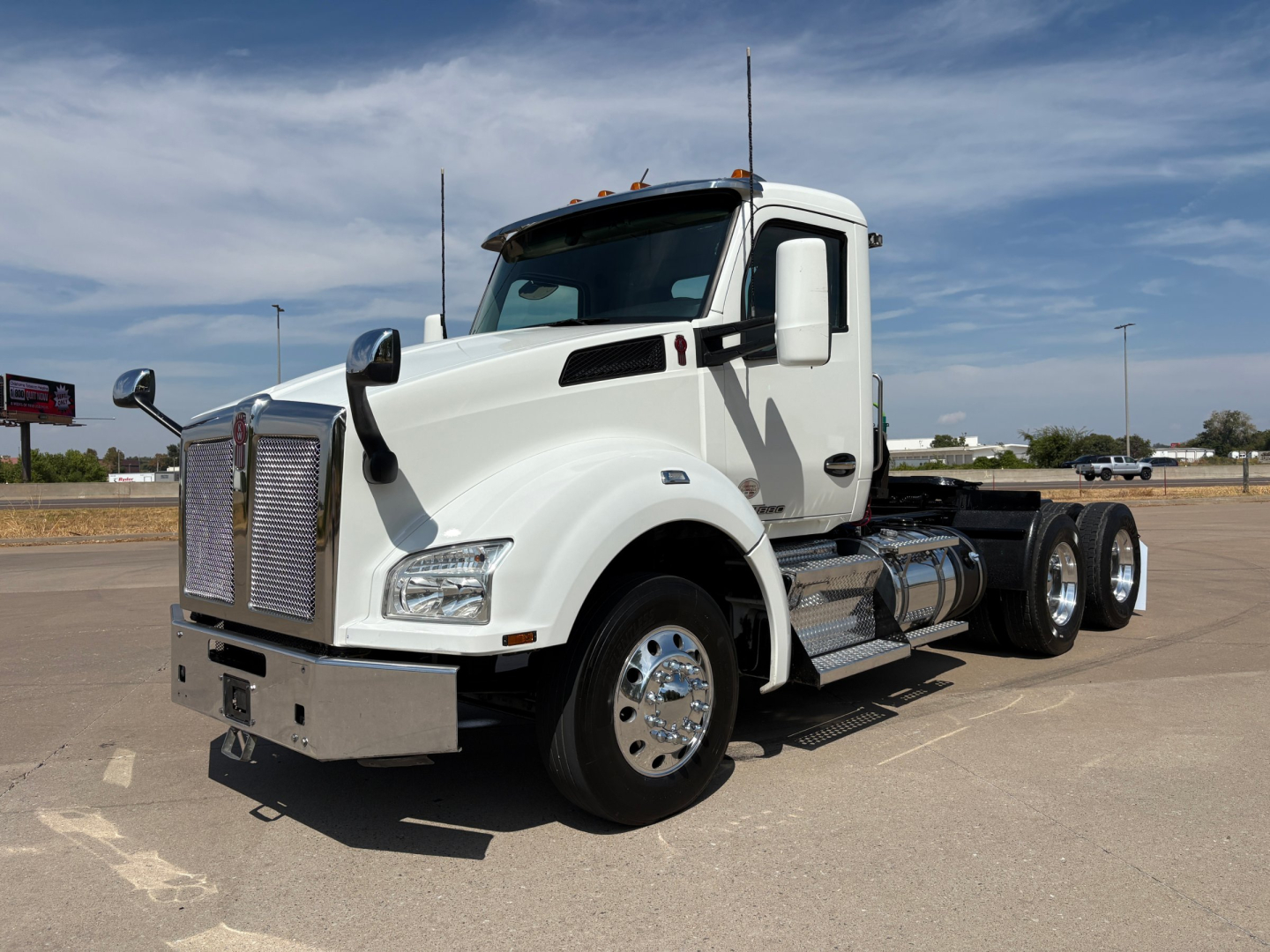 Truck chassis showing 2022 Kenworth T880 in white with dual rear axles and chrome fuel tanks.