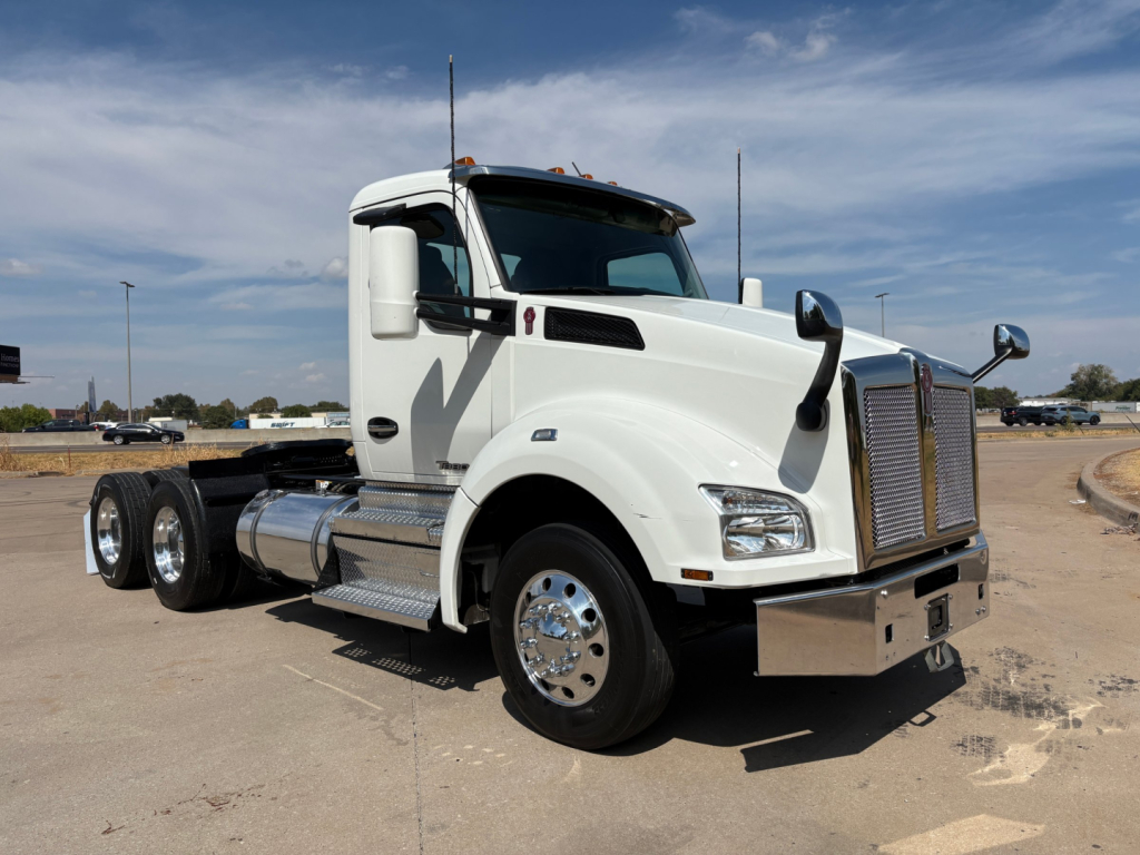 Kenworth T880 conventional daycab truck in white, side view showing dual rear axles and chrome fuel tanks.