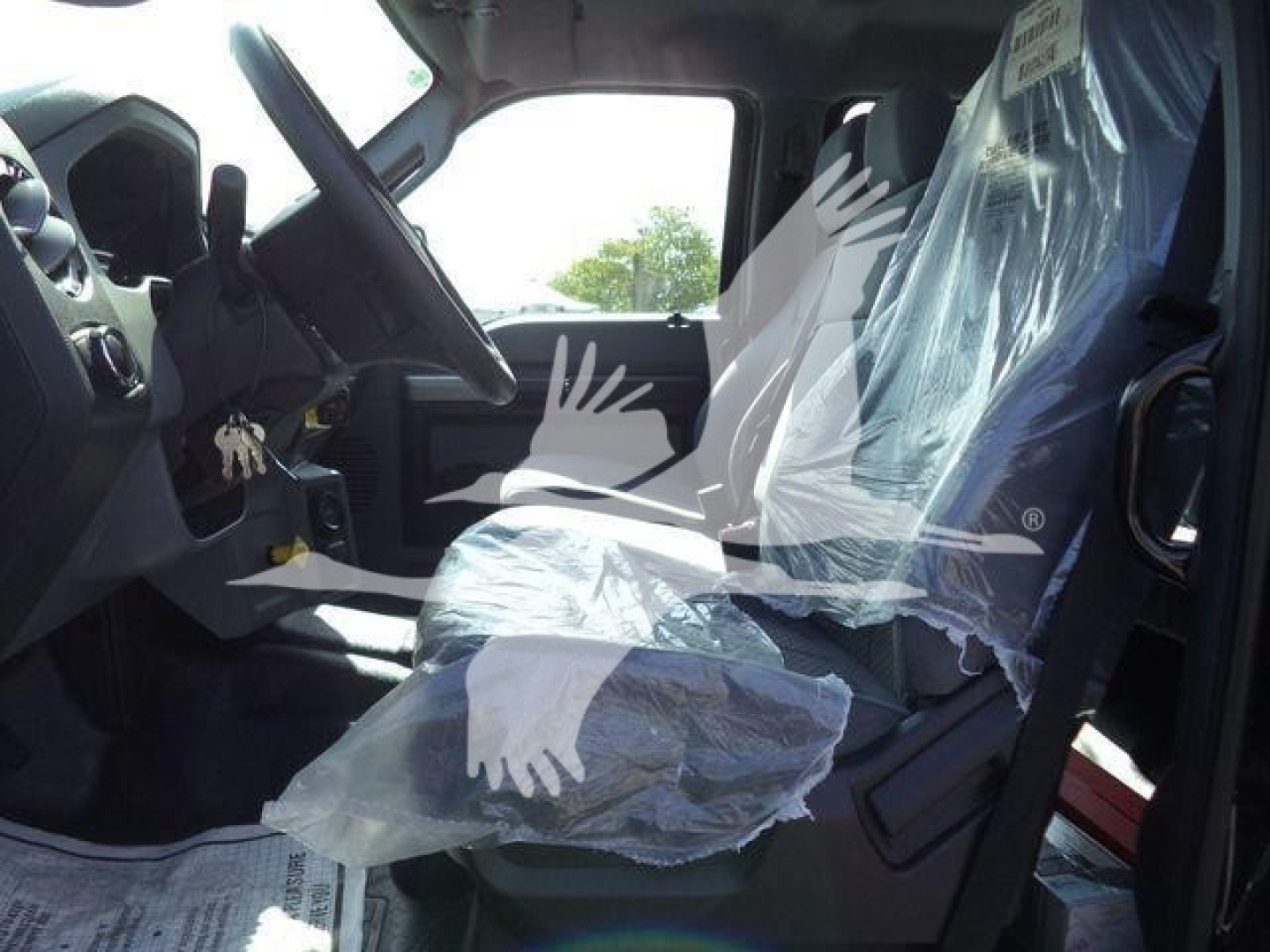 Ford F750 cab interior with wrapped plastic seat coverings and steering wheel visible, dashboard area, entry door open.