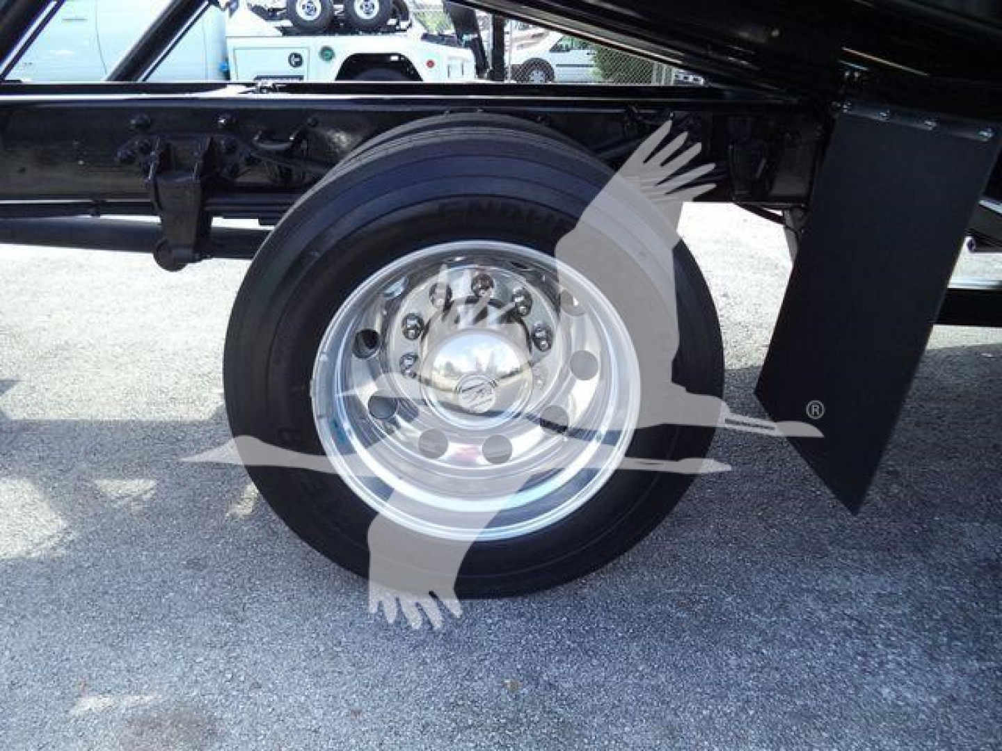 Ford F-750 rollback truck wheel and undercarriage view showing chrome wheel with lug nuts and black frame components.