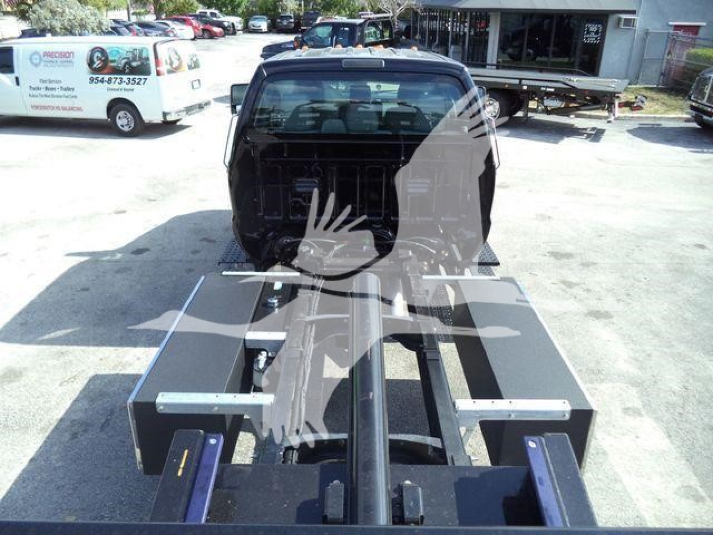 Truck cab and rollback-style chassis with mounting frame and hydraulic components visible; rear view shows the cab and flatbed framework ready for equipment installation.