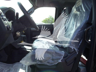 Ford F750 cab interior with wrapped plastic seat coverings and steering wheel visible, dashboard area, entry door open.