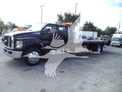 Ford F-750 rollback tow truck in black showing long flatbed, cab-front view with chrome grille and dual rear wheels.
