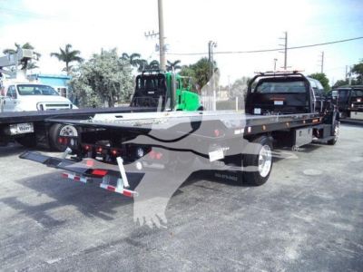 Ford F750 rollback tow truck flatbed rear view showing dual rear wheels and hydraulic winch system with safety straps and lights.