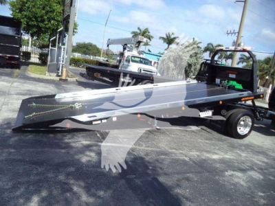 Ford F750 rollback tow truck bed in a stock image showing a long flatbed with hydraulic winch, side rails, and wheel hub details.